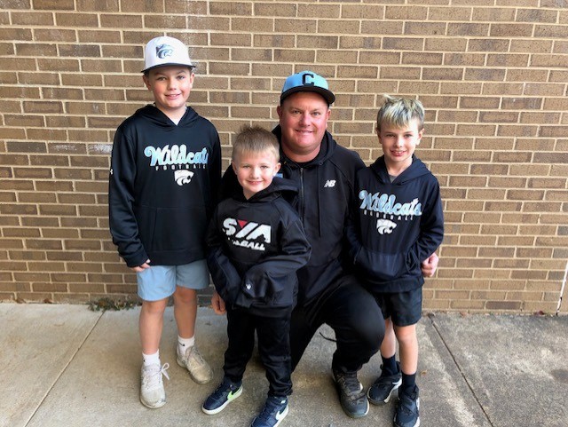 Little league coach posing with players