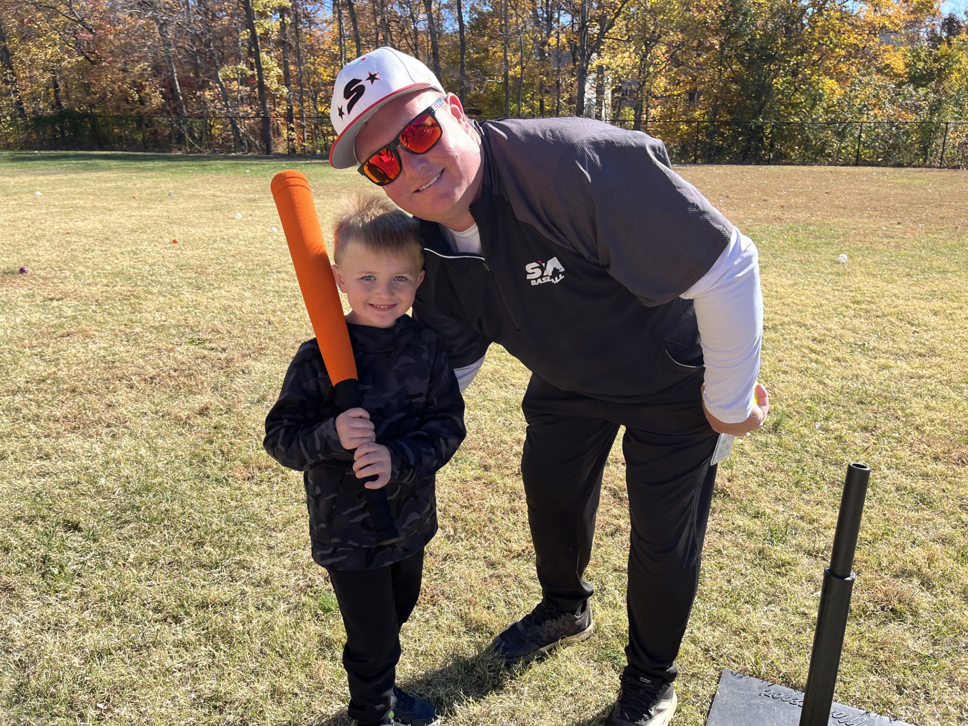 Little league coach posing with player