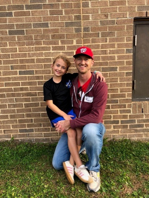 Little league coach posing with player