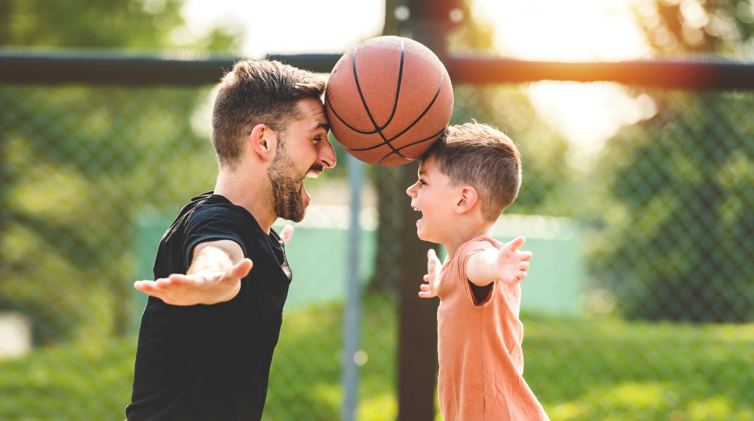 Father and son using foreheads to hold a basketball between them