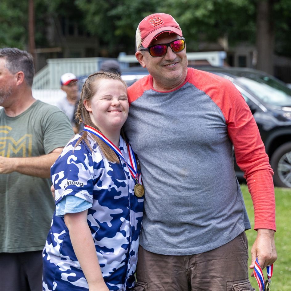 challenger ball player young woman in baseball uniform wearing a medal standing next to a coach
